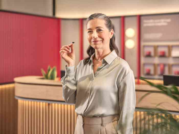 vrouw die een gehoorapparaat vasthoudt