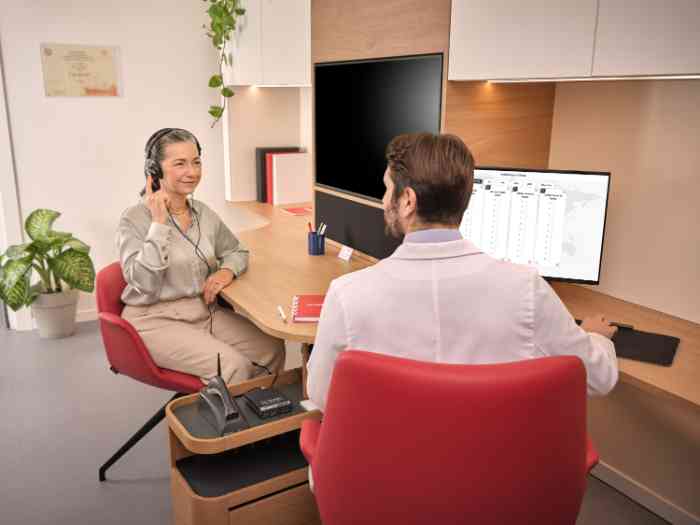 Audiologist fitting a hearing aid in client’s left ear