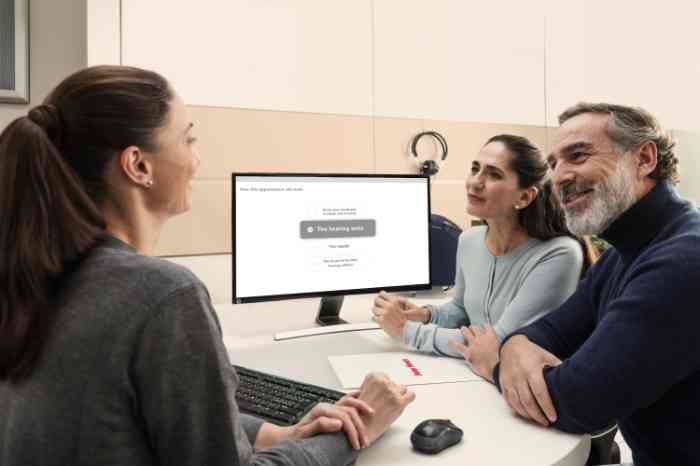 Audiologist fitting a hearing aid in client’s left ear