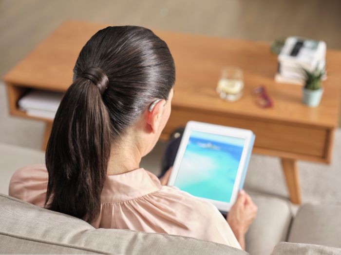 Vrouw met hoortoestellen die naar een laptop kijkt