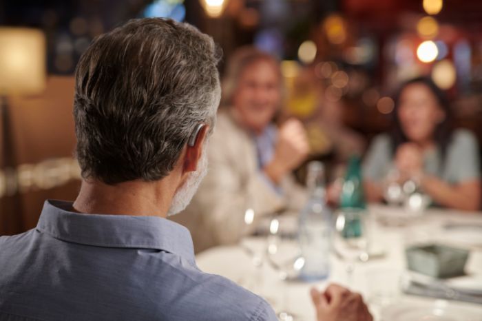 Een man die een hoortoestel draagt in een druk restaurant