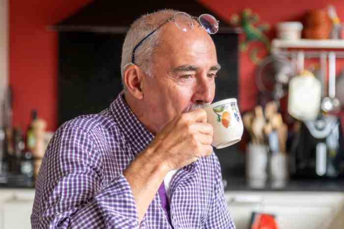 Man met hoortoestel drinkt koffie